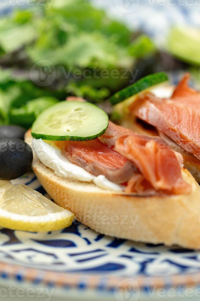 Freshly made open-faced sandwiches topped with smoked salmon and cucumber, served with a side salad photo