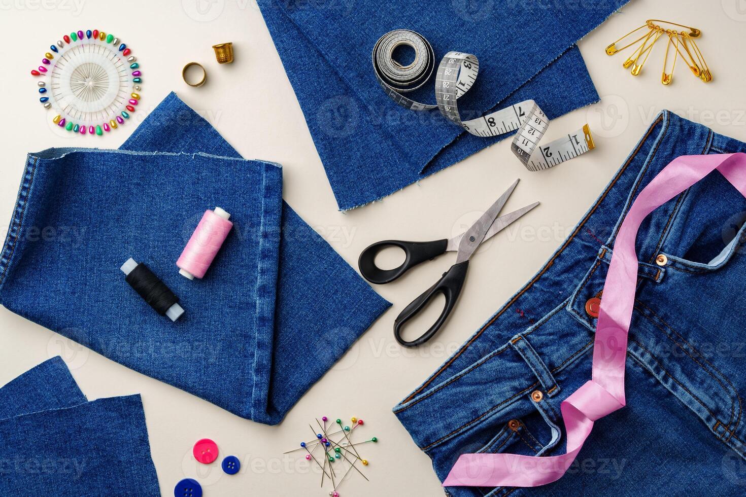 Sewing supplies and denim fabric arranged on a workspace for clothing alterations in a bright setting photo