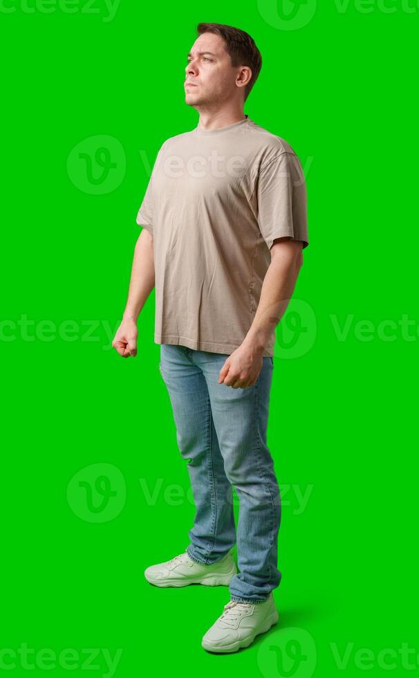 Young man stands confidently in a plain beige t-shirt and jeans against a bright green background photo