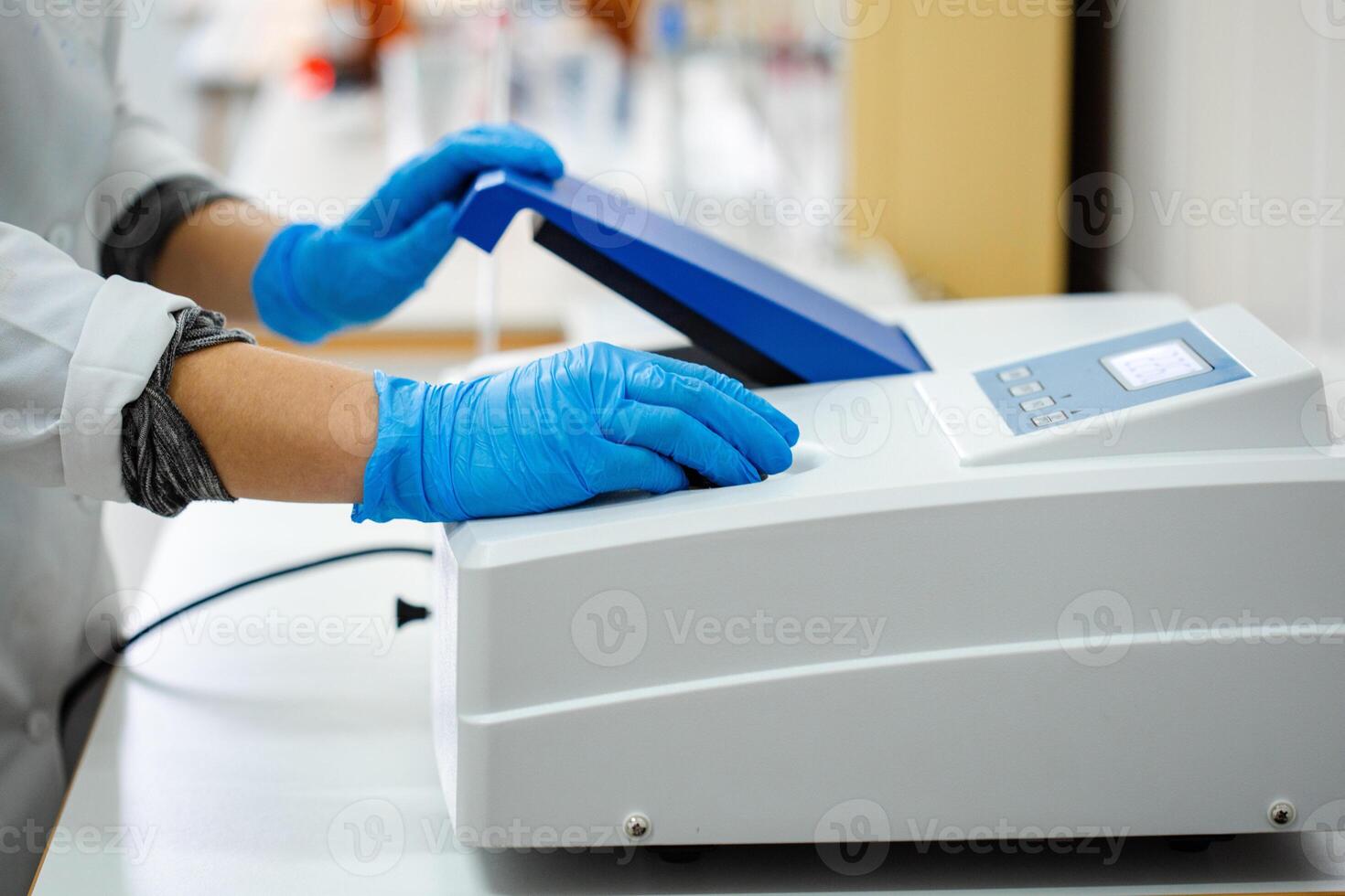 Laboratory technician operates scientific equipment for research in a clinical setting during daytime hours photo