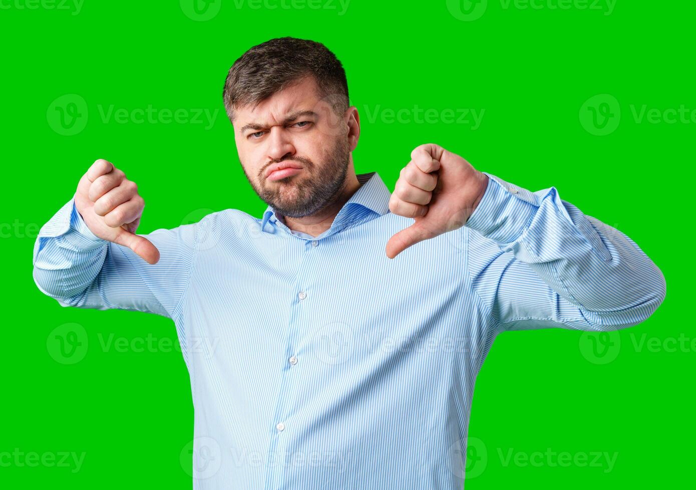 Man expressing disapproval with thumbs down gesture against a bright green background photo