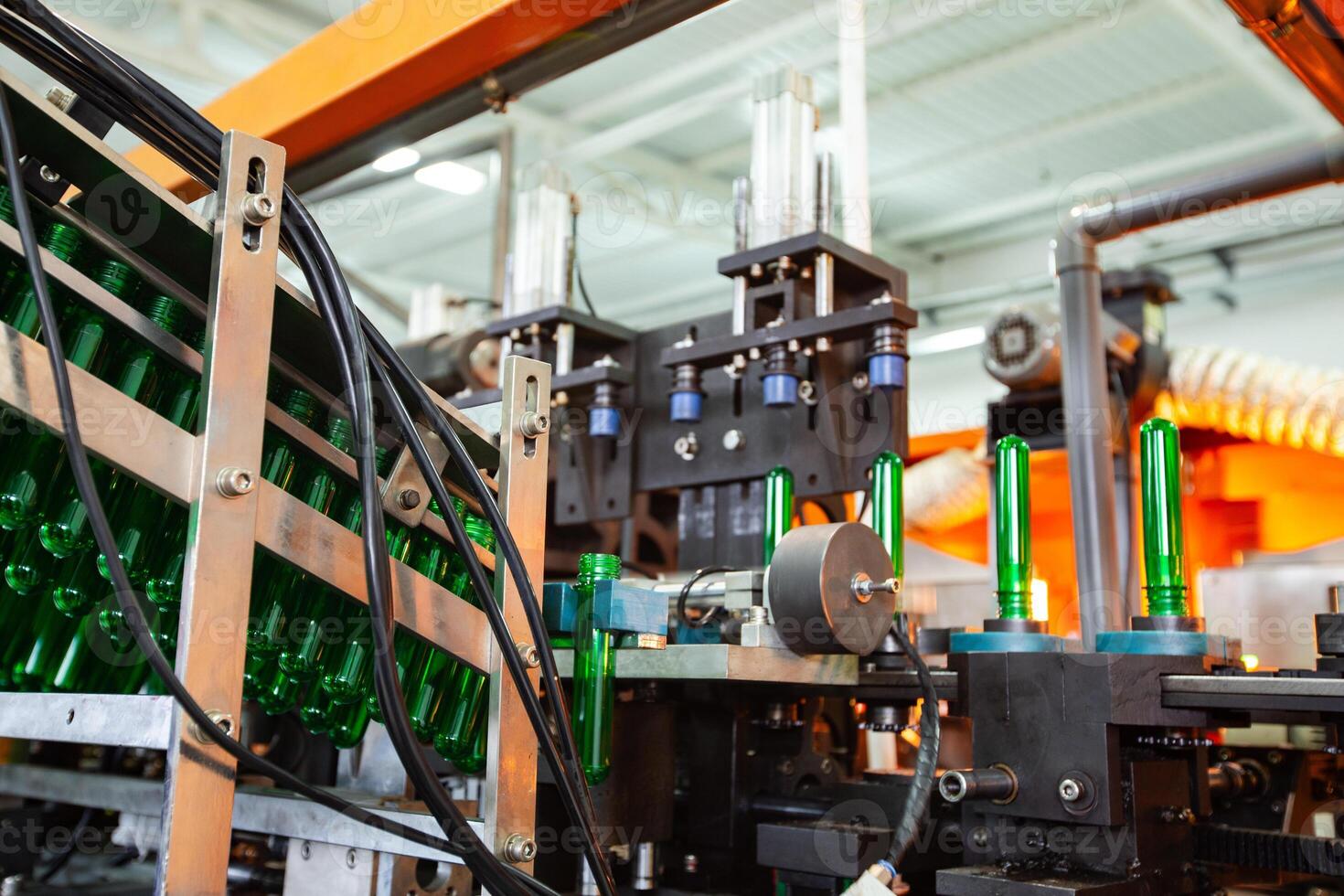 Machine assembling green glass bottles in a factory during daylight hours photo
