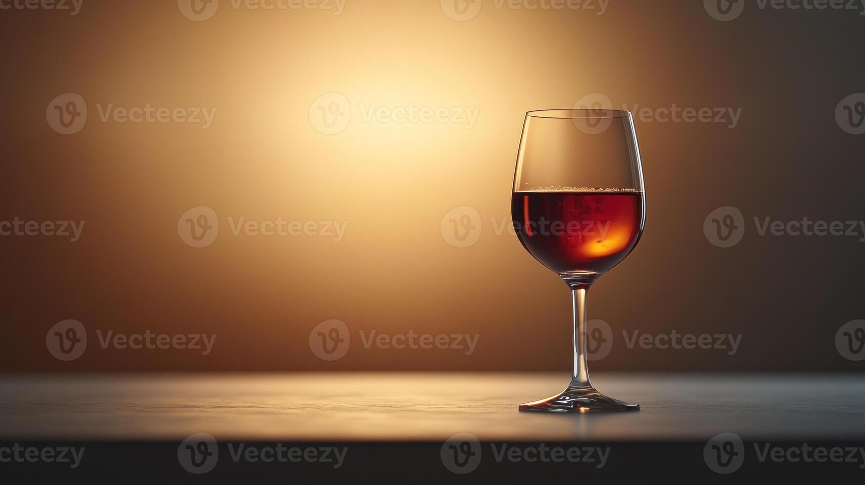 A glass of rich red wine rests elegantly on a warmly lit polished surface photo