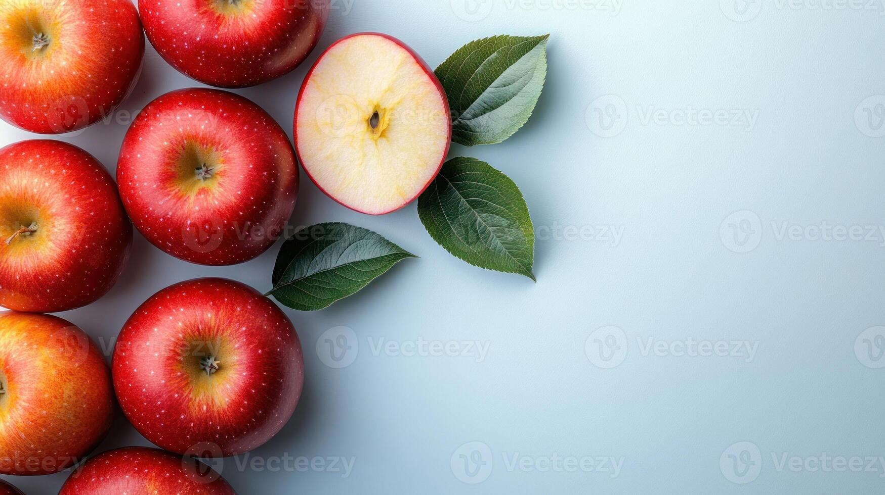 Bright red apples are arranged, one sliced to show its crisp white interior photo
