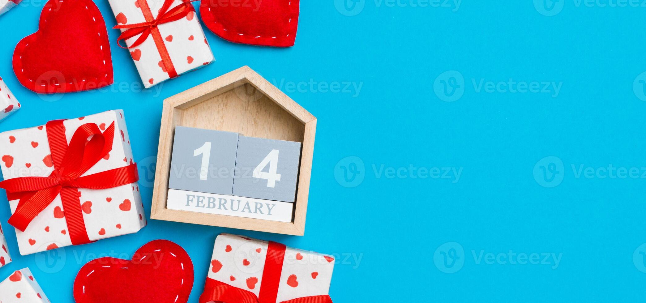 Holiday composition of gift boxes, wooden and red textile hearts on colorful background with empty space for your design. The fourteenth of February. Top view of Valentine's Day concept photo