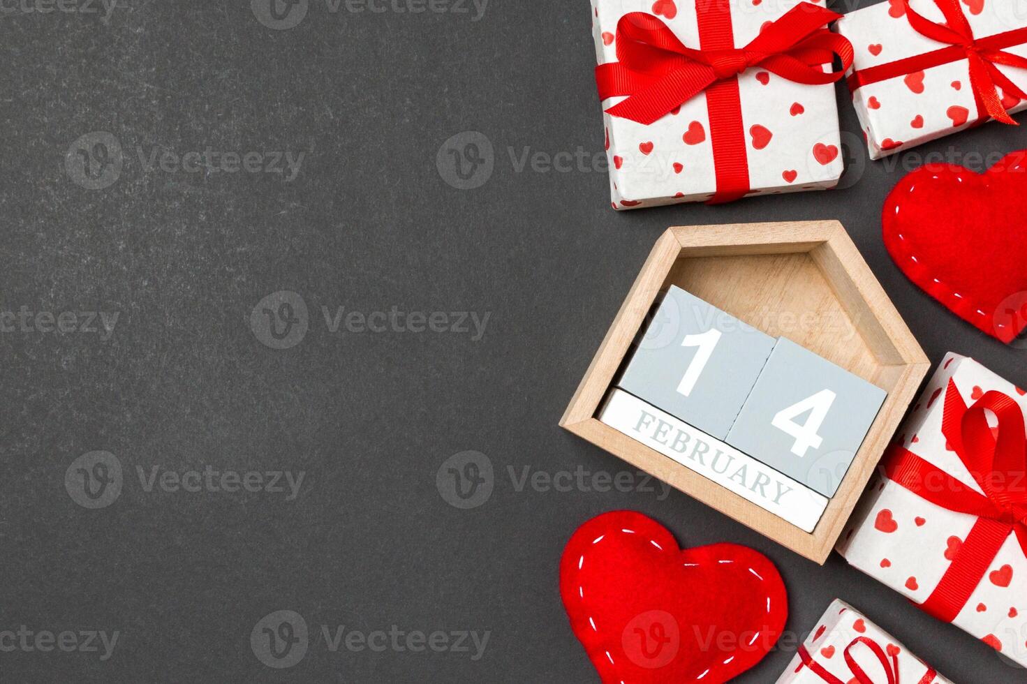 Holiday composition of gift boxes, wooden calendar red textile hearts on colorful background with empty space for your design. The fourteenth of February. Top view of Valentine's Day concept photo
