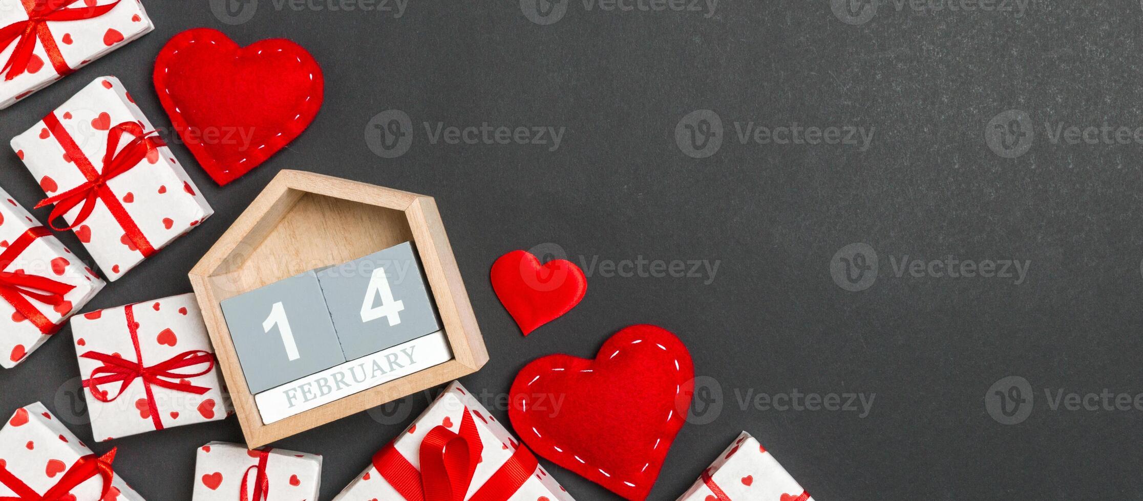 Top view of gift boxes, wooden calendar and red textile hearts colorful background. The fourteenth of february. St Valentine's day concept with copy space photo