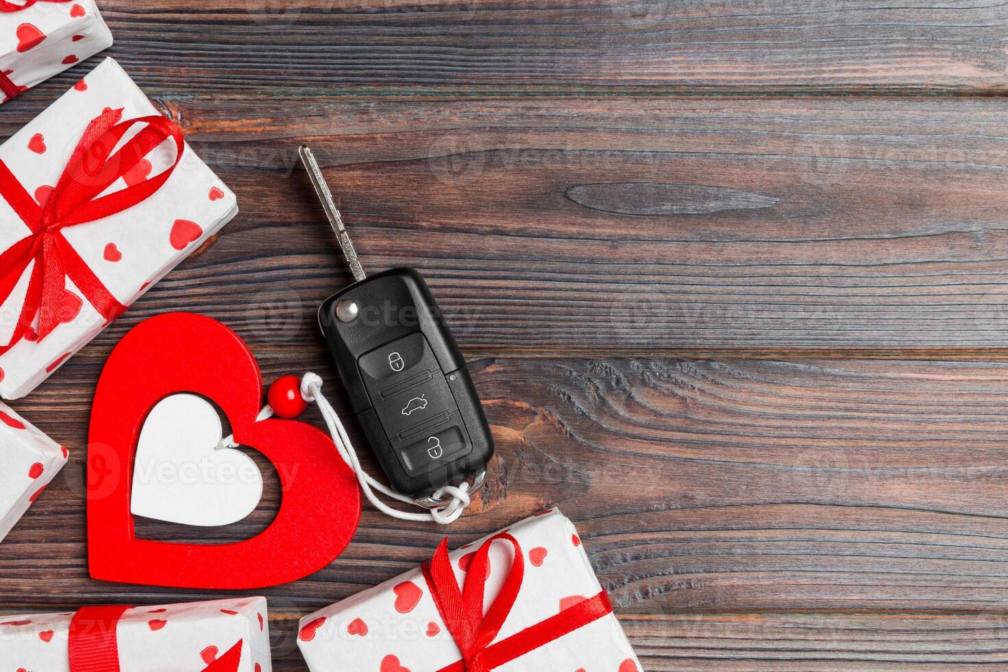 Top view of a present for Valentine Day on wooden background. Car key, gift boxes and heart with copy space. Surprise concept for a holiday photo