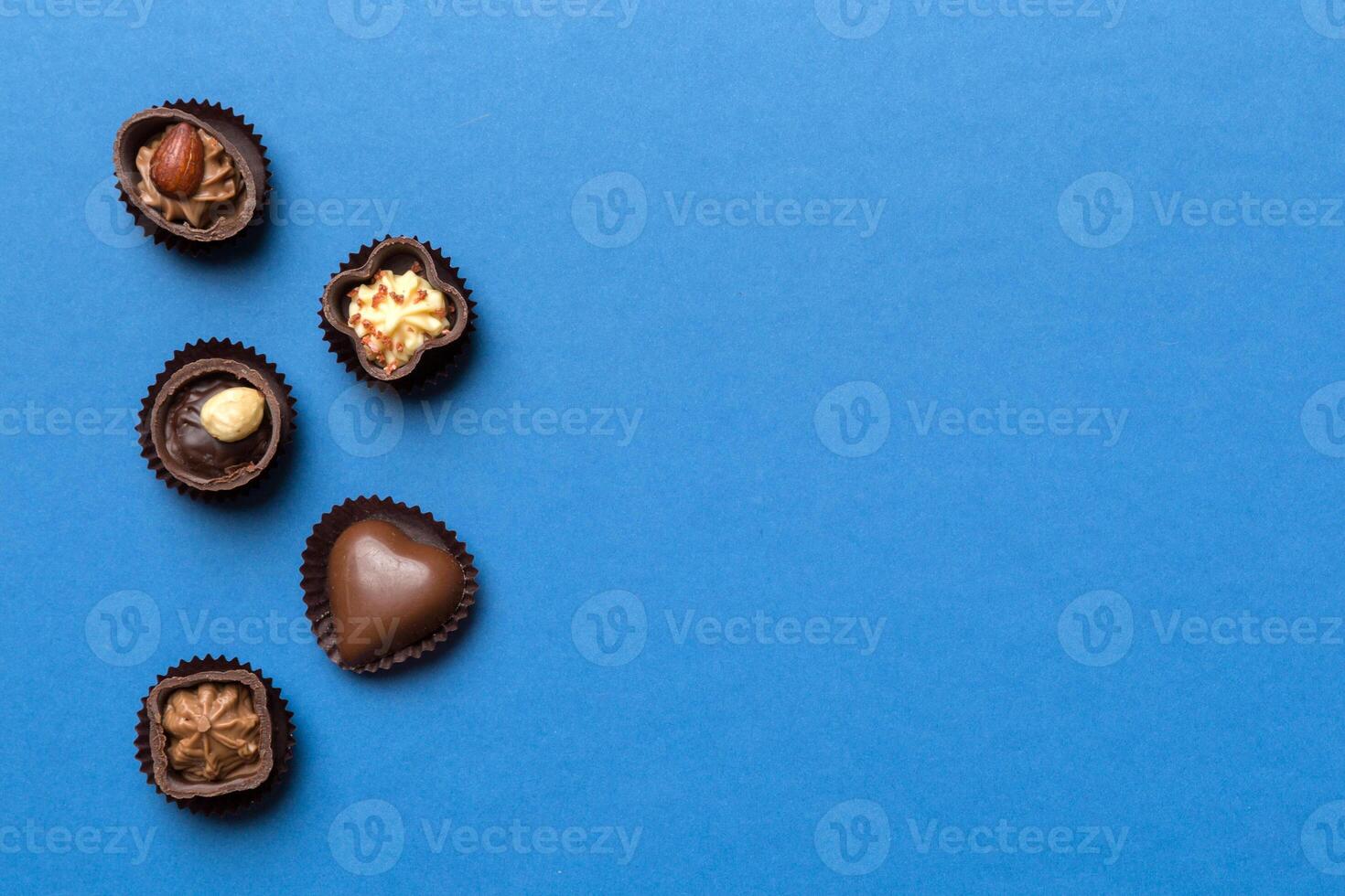 Different kinds of chocolates on colored table close-up. View and Flat Lay with copy space photo