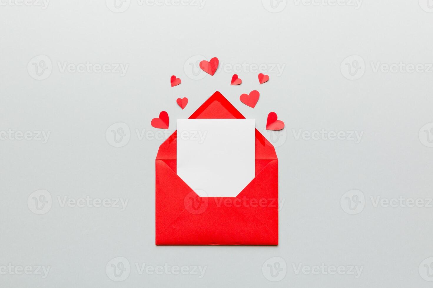 Red paper envelope with empty white card and heart colored background. top view valentines day concept photo
