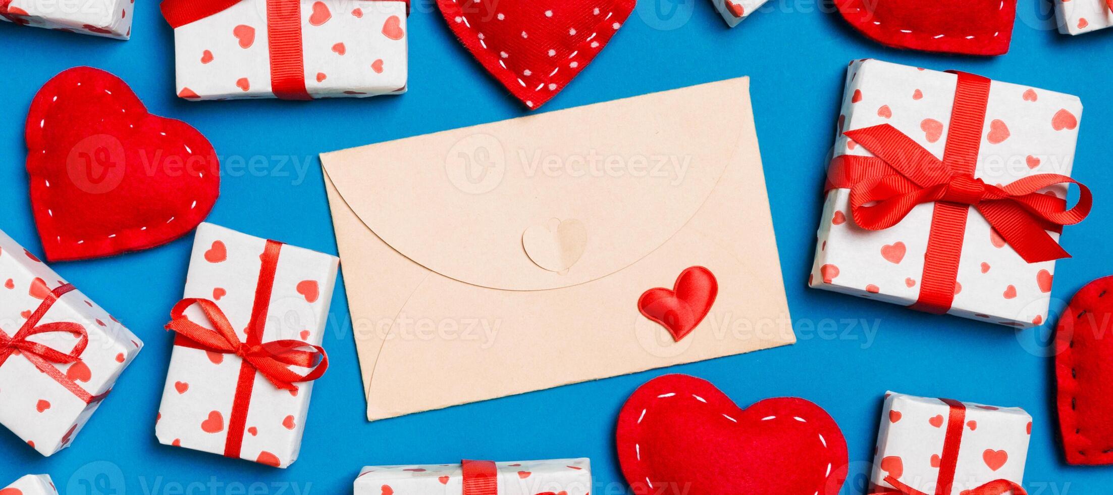 Top view of colorful background made of craft envelope, gift boxes and red textile hearts. Valentine's Day concept photo