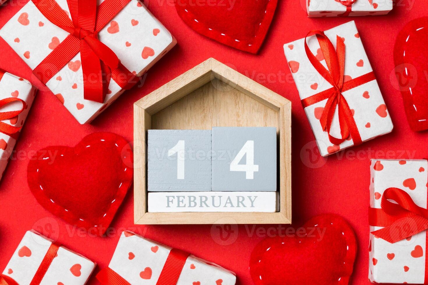 Top view of wooden calendar white gift boxes and red textile hearts on colorful background. Valentine's Day concept photo