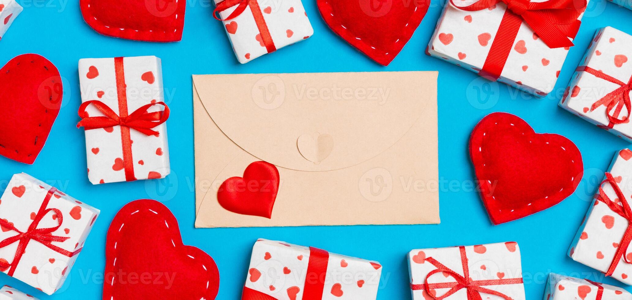 Top view colorful valentine background made of craft envelope, gift boxes and red textile hearts. Valentine's Day concept photo