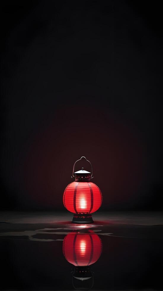 A red lantern rests against a dark background, its reflection softly visible, with room for text in the surrounding space. photo