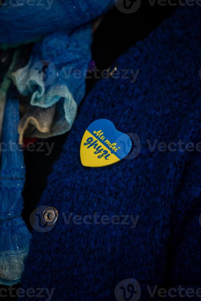 Close Up of Blue Garment with Heart Shaped Pin and Cyrillic Text photo