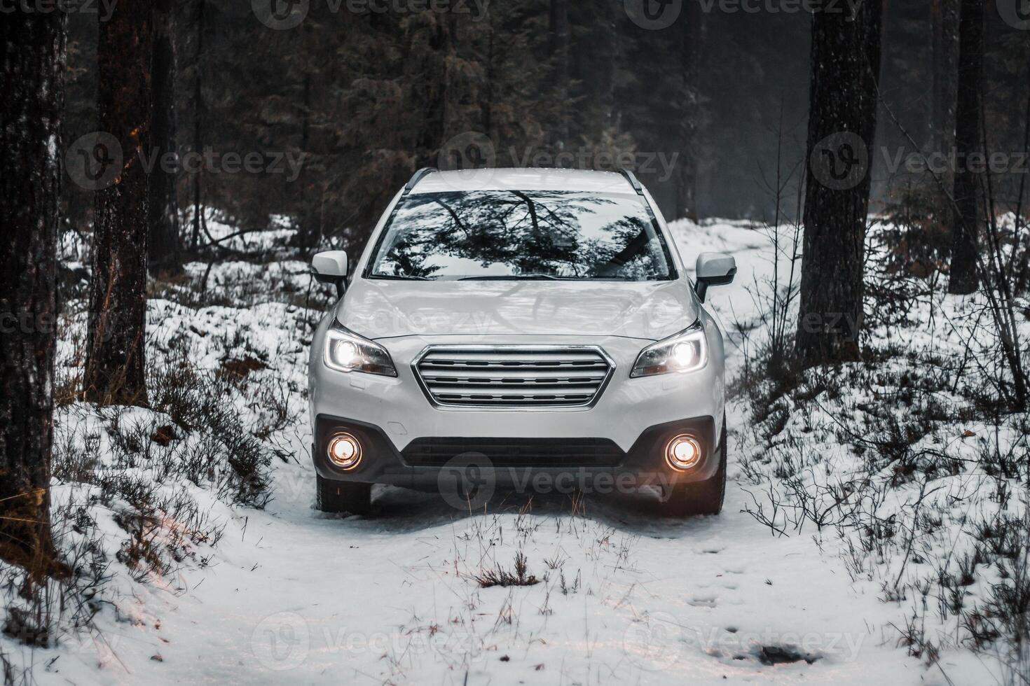 White SUV on Snow Covered Path in a Forested Winter Landscape photo