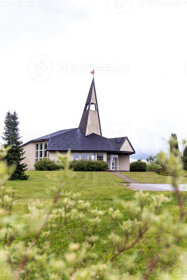 Small Church with Triangular Steeple and Paved Pathway on Cloudy Day photo