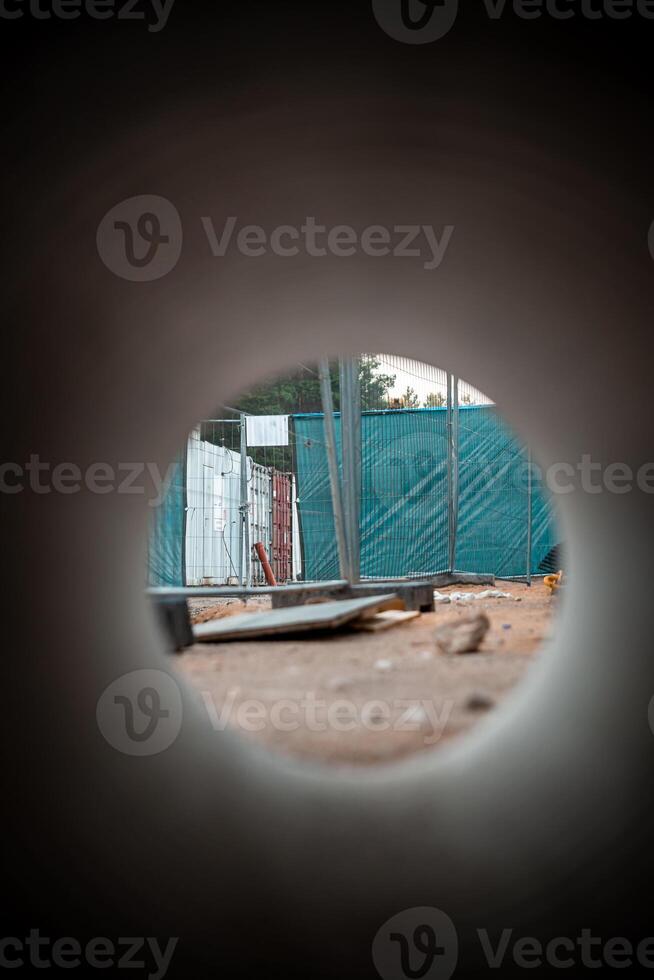 View Through Circular Pipe Framing a Construction Site with Trees photo