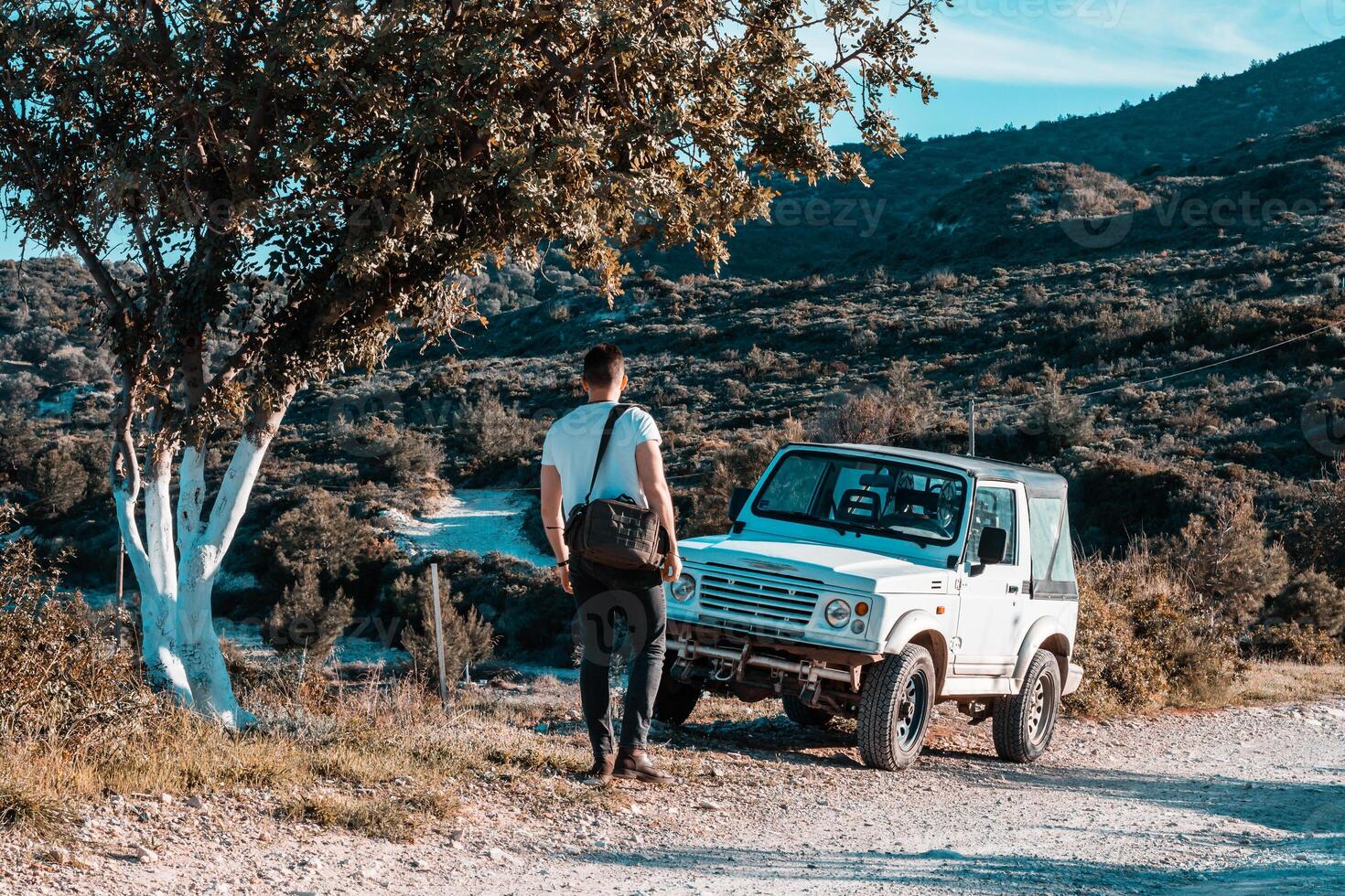 Man with White Off Road Vehicle on Dirt Path in Rugged Terrain photo