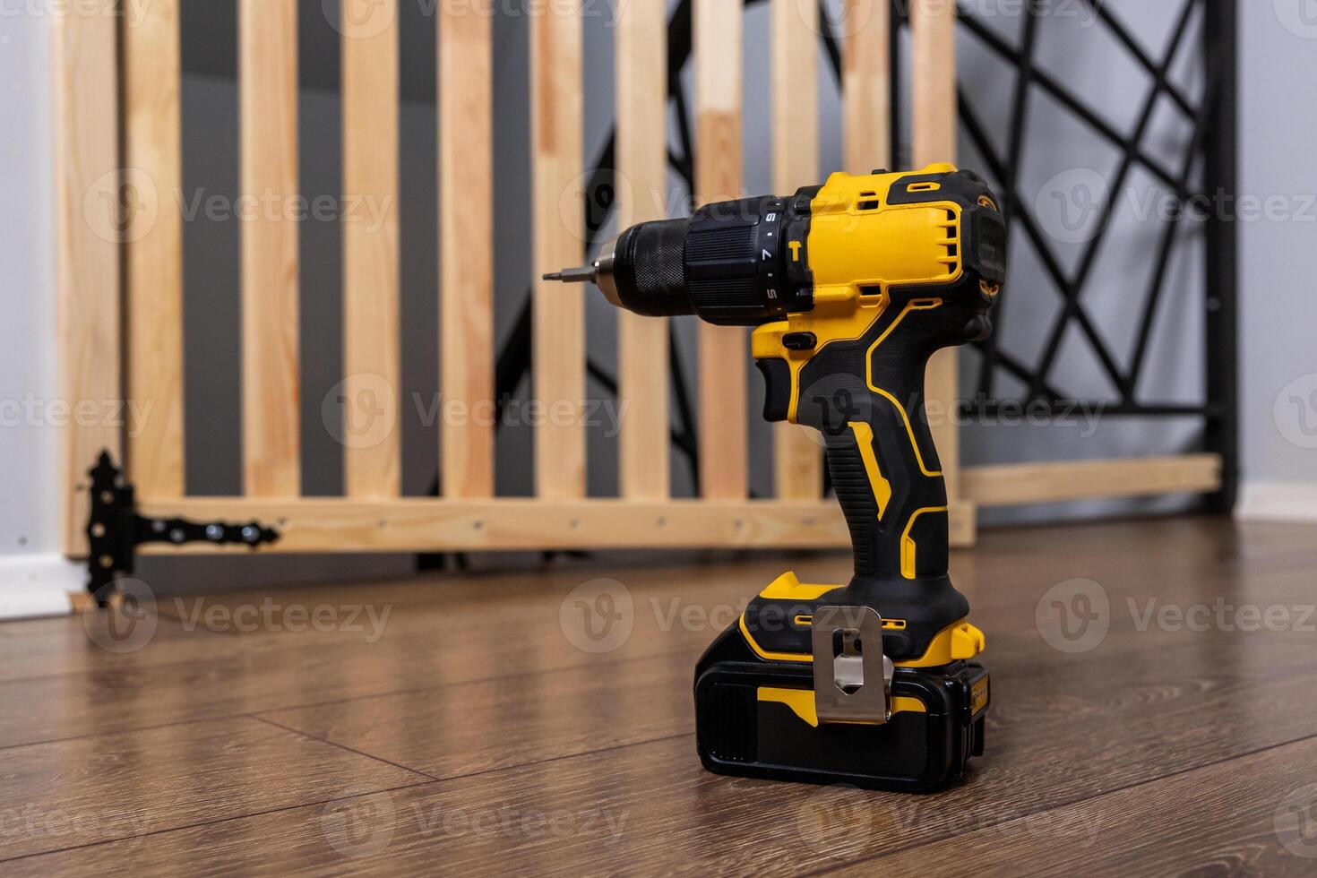Yellow and Black Cordless Drill with Partially Assembled Baby Gate photo