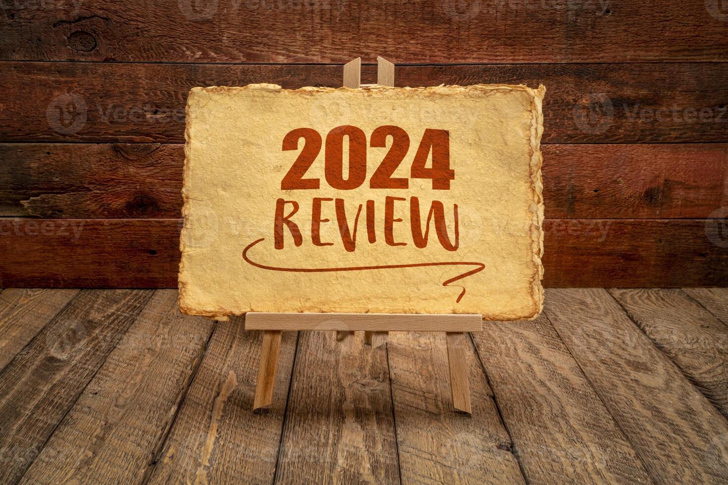2024 year review - easel sign with antique paper against rustic wood, end of year business concept photo
