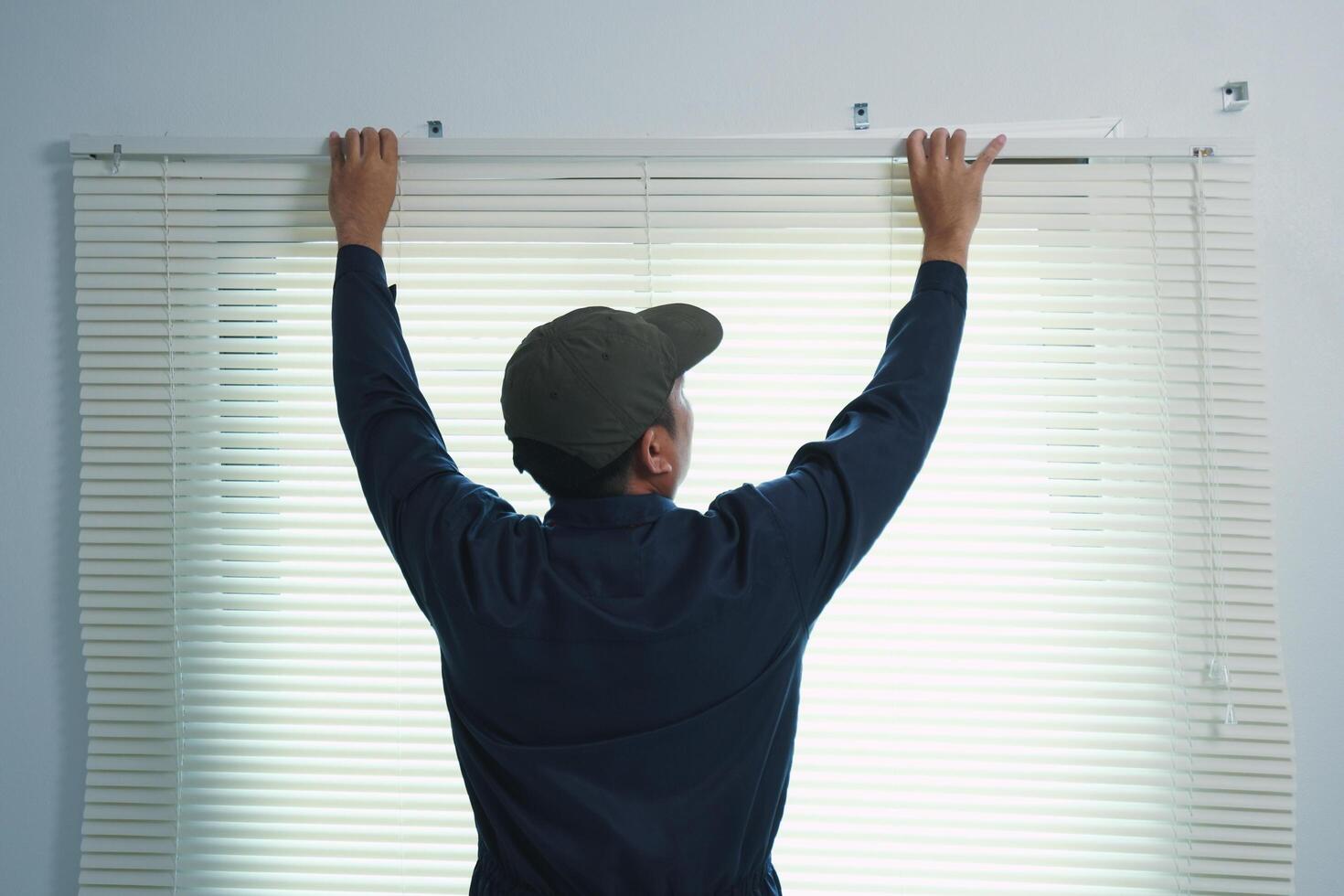 A curtain installer is installing curtains at a customer's house. Window in a room. photo