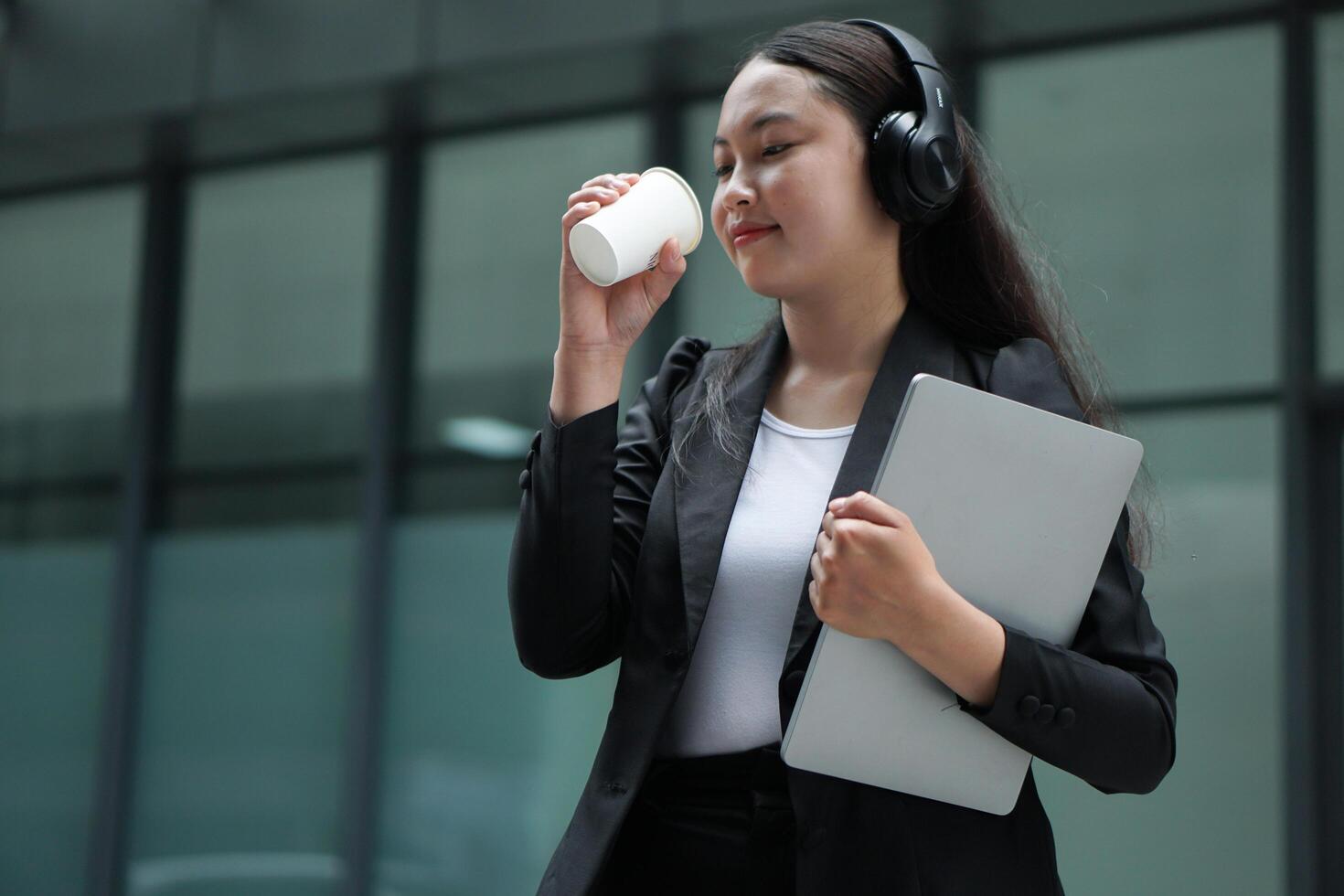 Asian girlfriend wearing earphones while drinking coffee and holding travel-sized locking strip in other hand photo