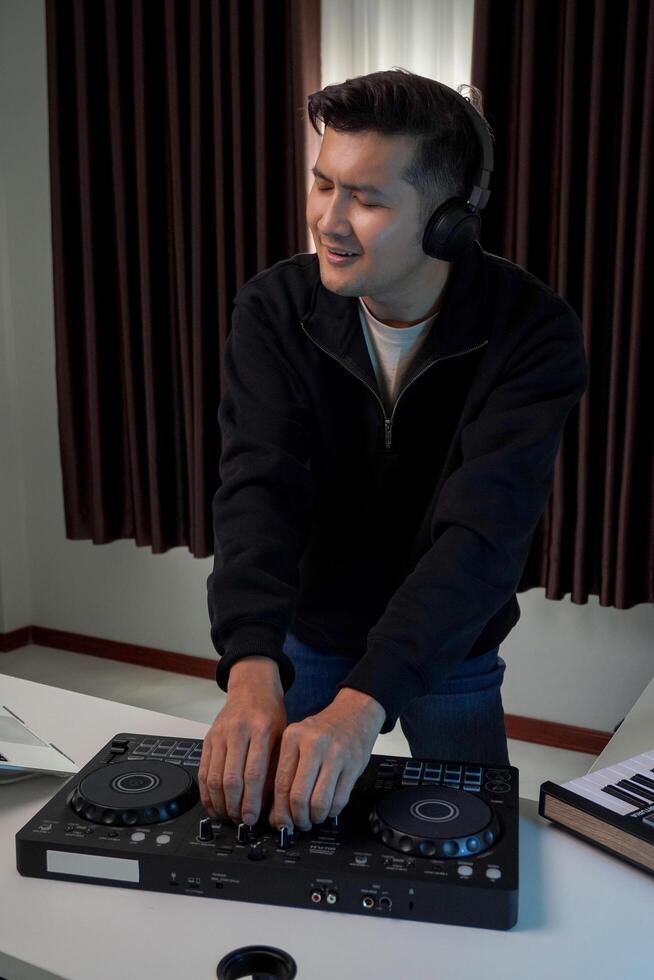 Asian DJ is happily playing music at home. Practice concept of playing music at home. photo