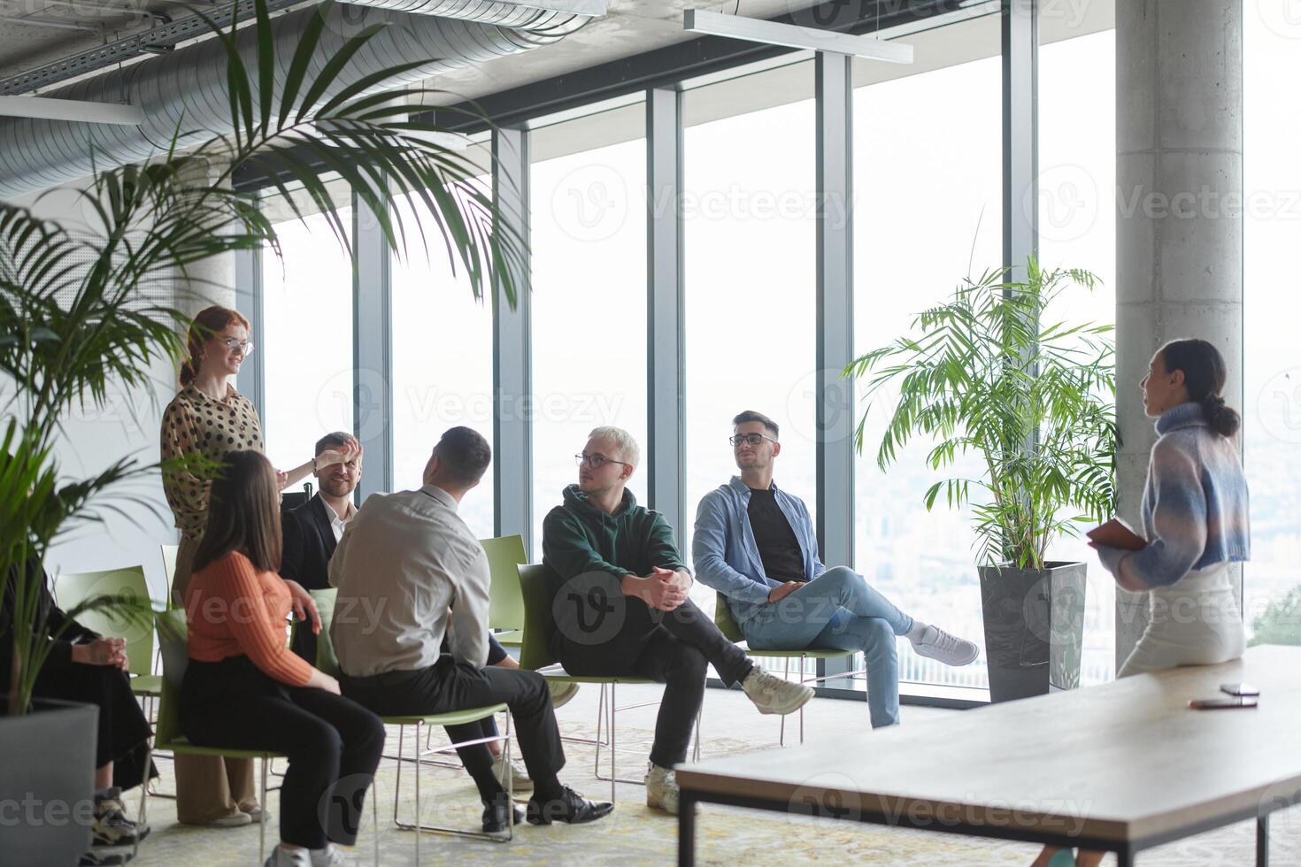 A diverse group of business professionals sits attentively in a modern office, actively participating in a training session led by an instructor, focusing on the latest technological advancements in photo