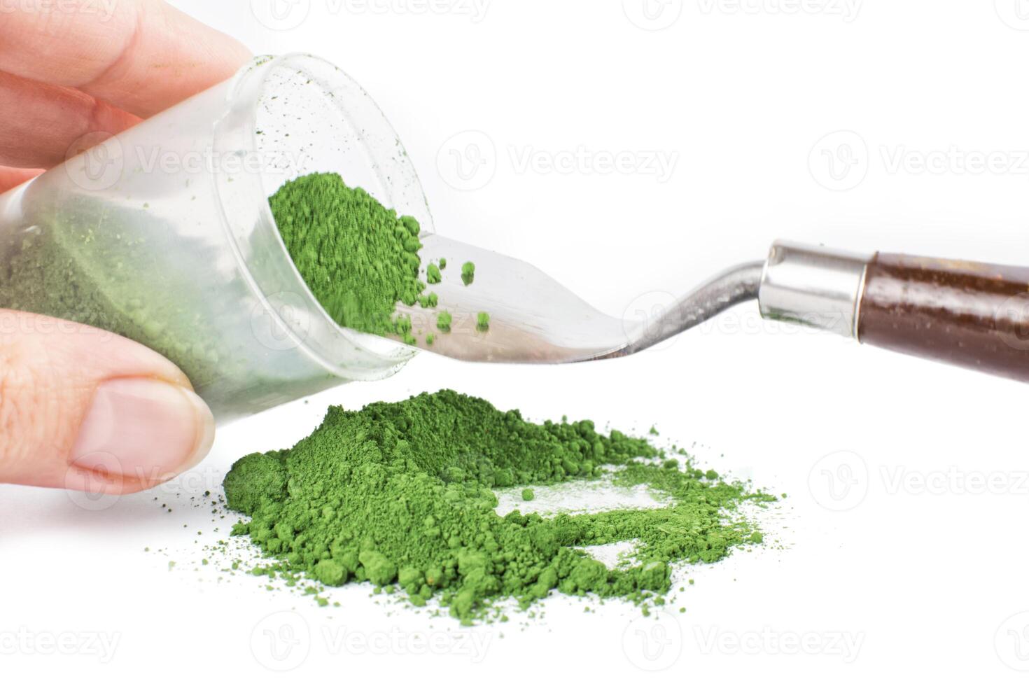 Green Earth, Green Powder Spills From a Jar Onto a Clean Surface With a Scoop Nearby Ready for Use photo