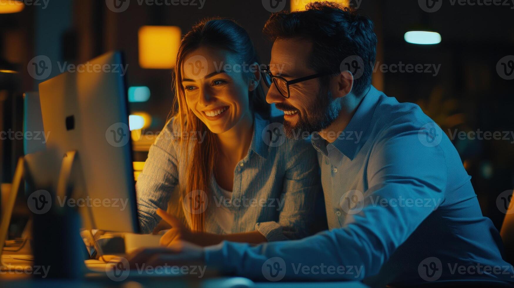 A Couple Collaborating on a Project, Working Together on a Computer in a Dimly Lit Office Setting photo