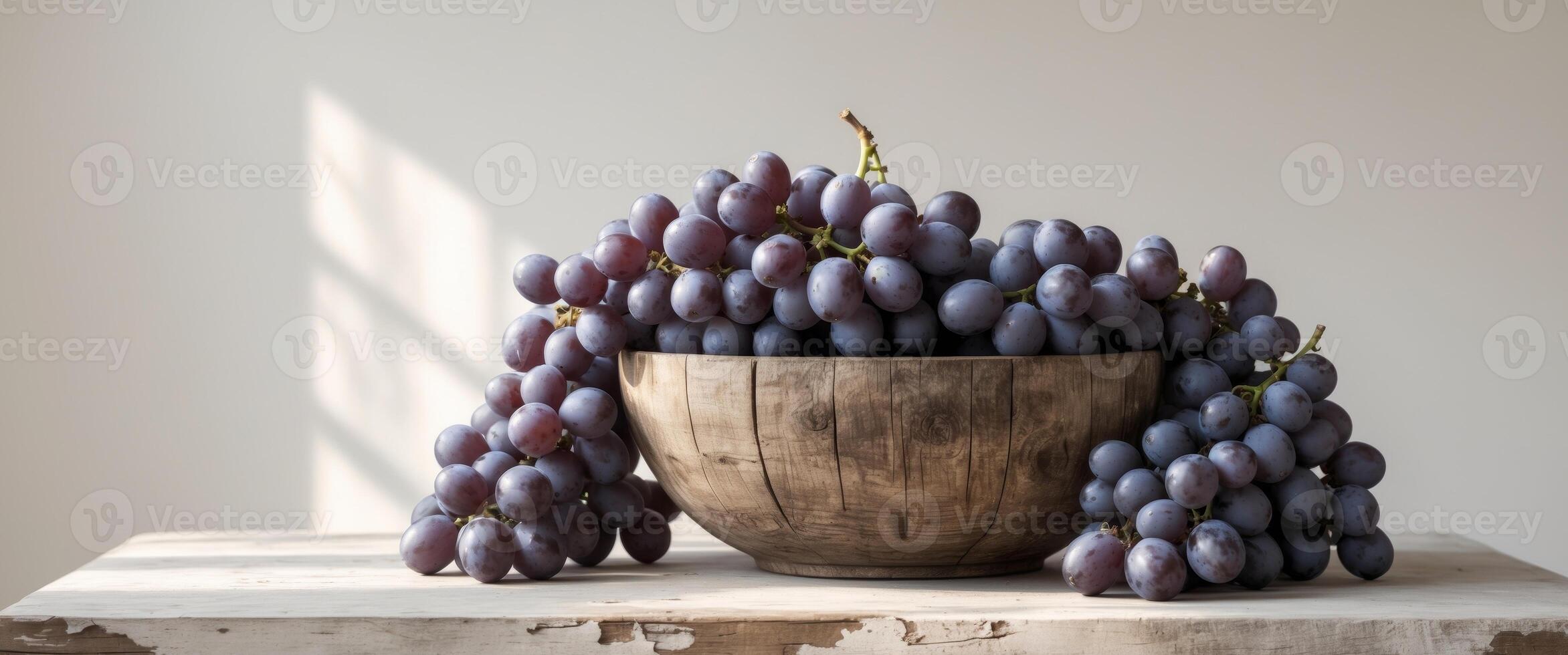 Black grapes in a wooden bowl on a table. photo