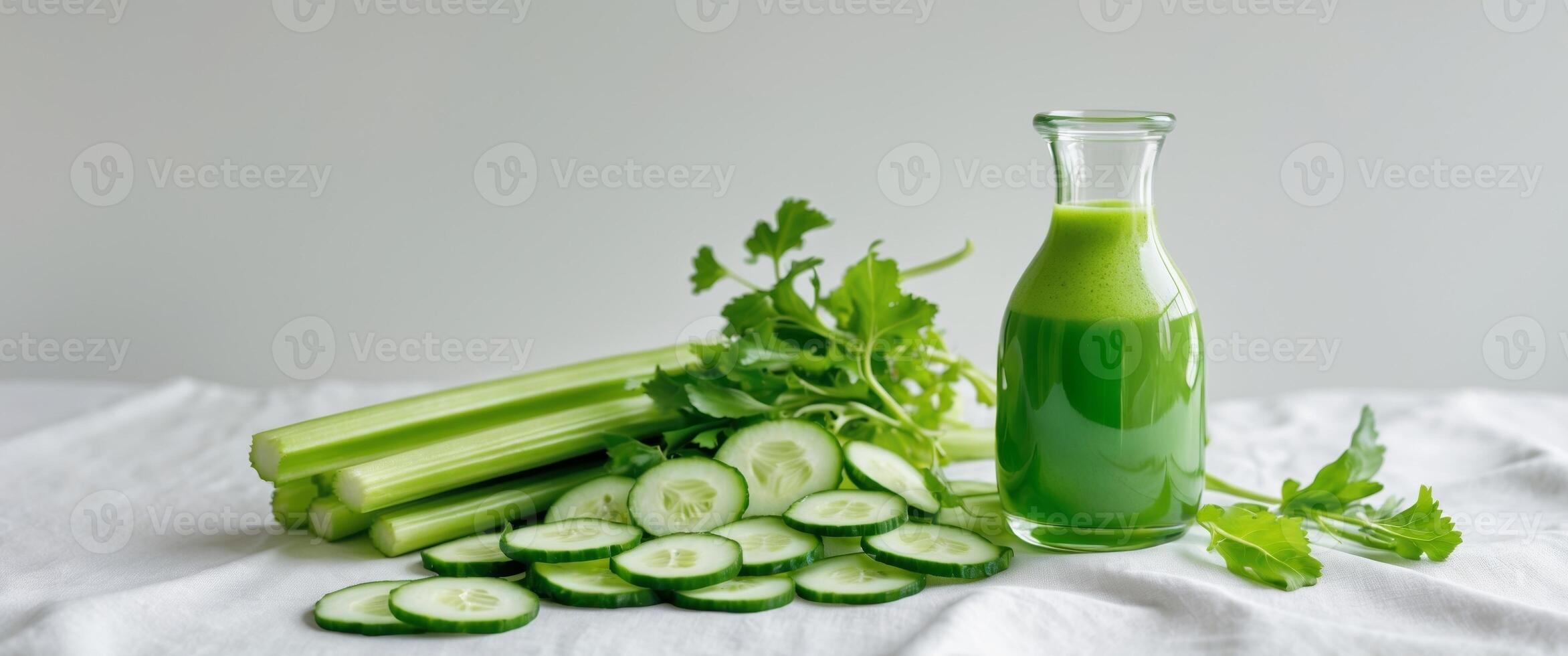A vibrant green juice in a clear glass bottle with celery and cucumber slices beside it. photo
