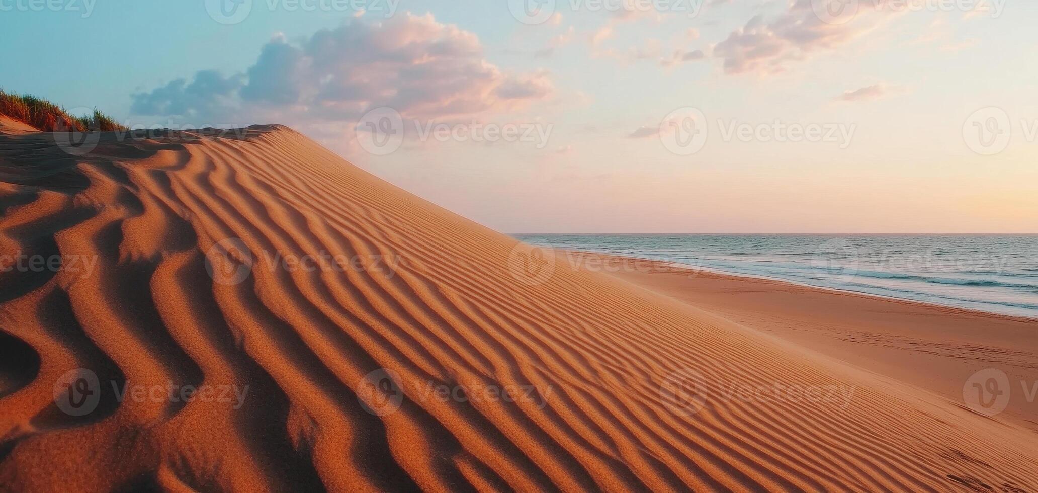 Ripples of sand lead towards towering dune under colorful sky, creating serene beach landscape at sunset. gentle waves add to tranquil atmosphere photo