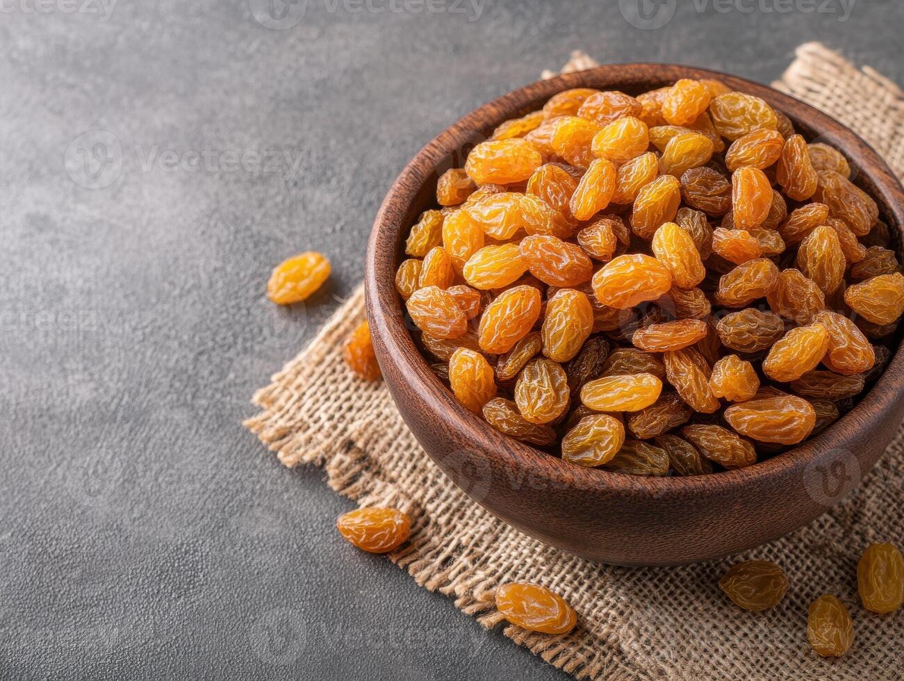 bowl of golden raisins on burlap cloth, showcasing their rich texture and color. Perfect for snacking or adding to recipes, these dried fruits offer sweet and nutritious option photo