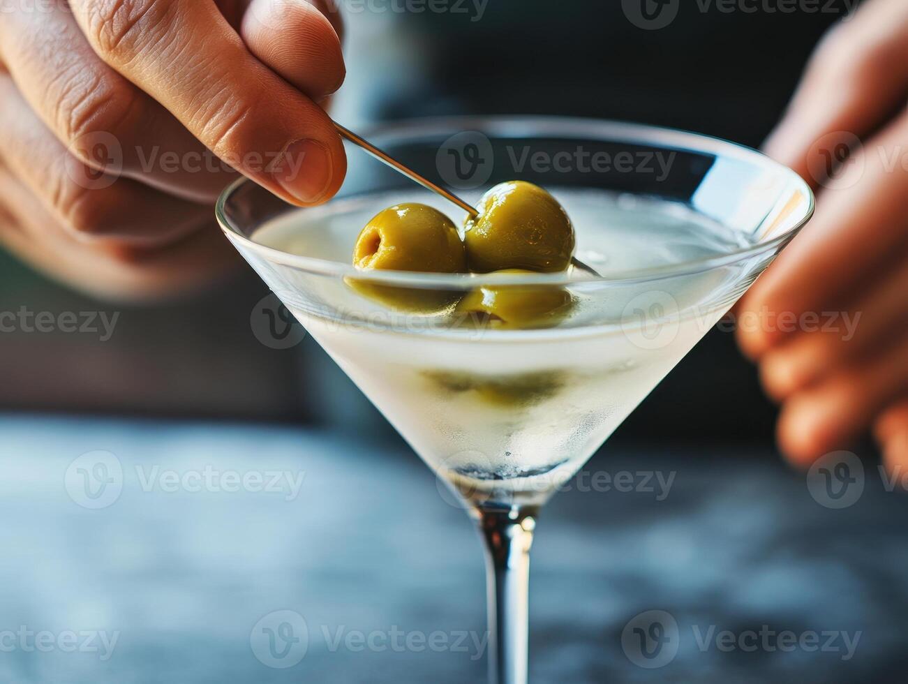 bartender hands carefully garnish martini with olives, showcasing art of cocktail preparation. elegant glass reflects sophistication of mixology photo