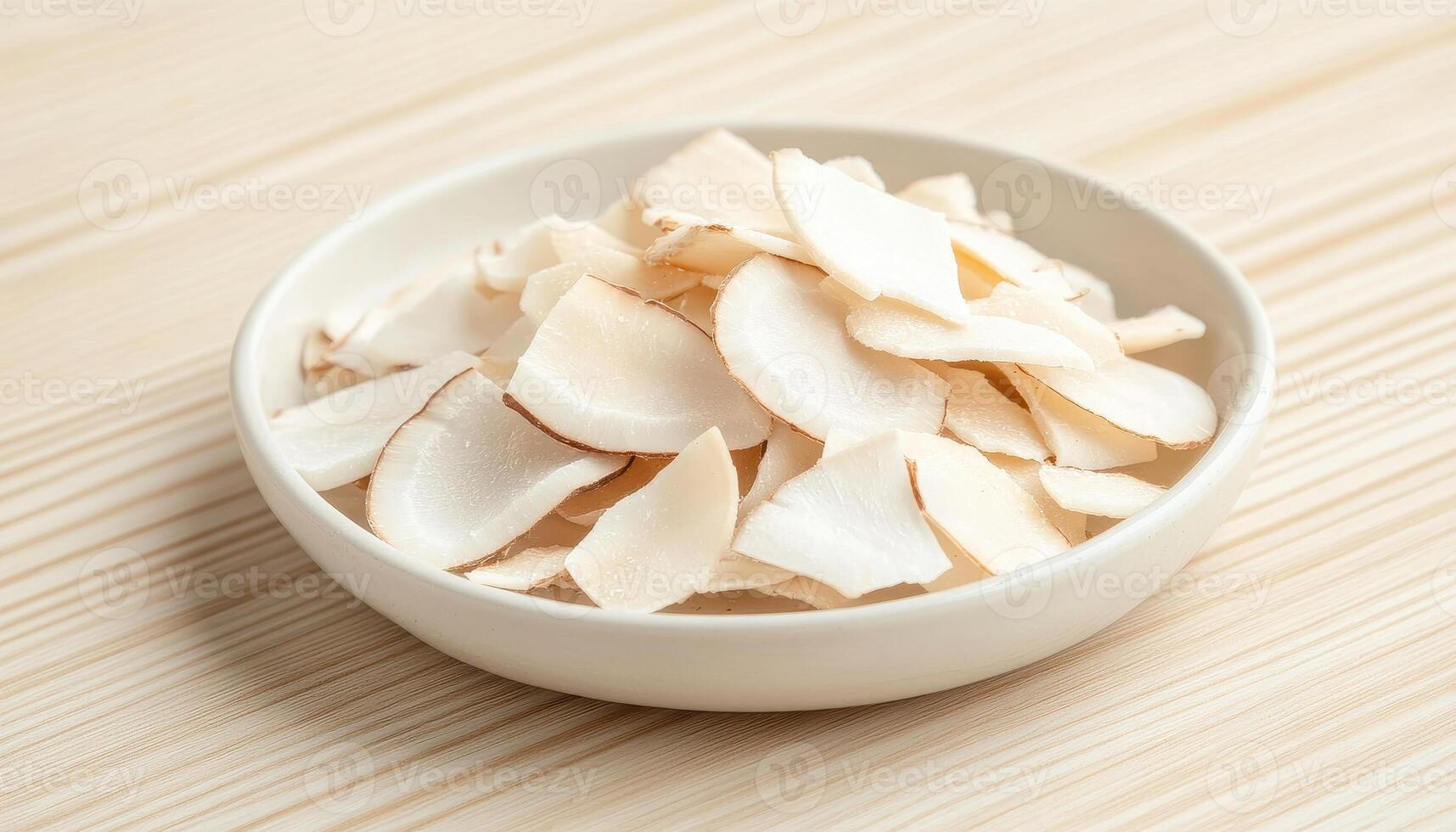 Dried coconut chips on white ceramic plate, showcasing healthy snack option. These crispy, light slices are perfect for adding flavor to dishes or enjoying on their own photo
