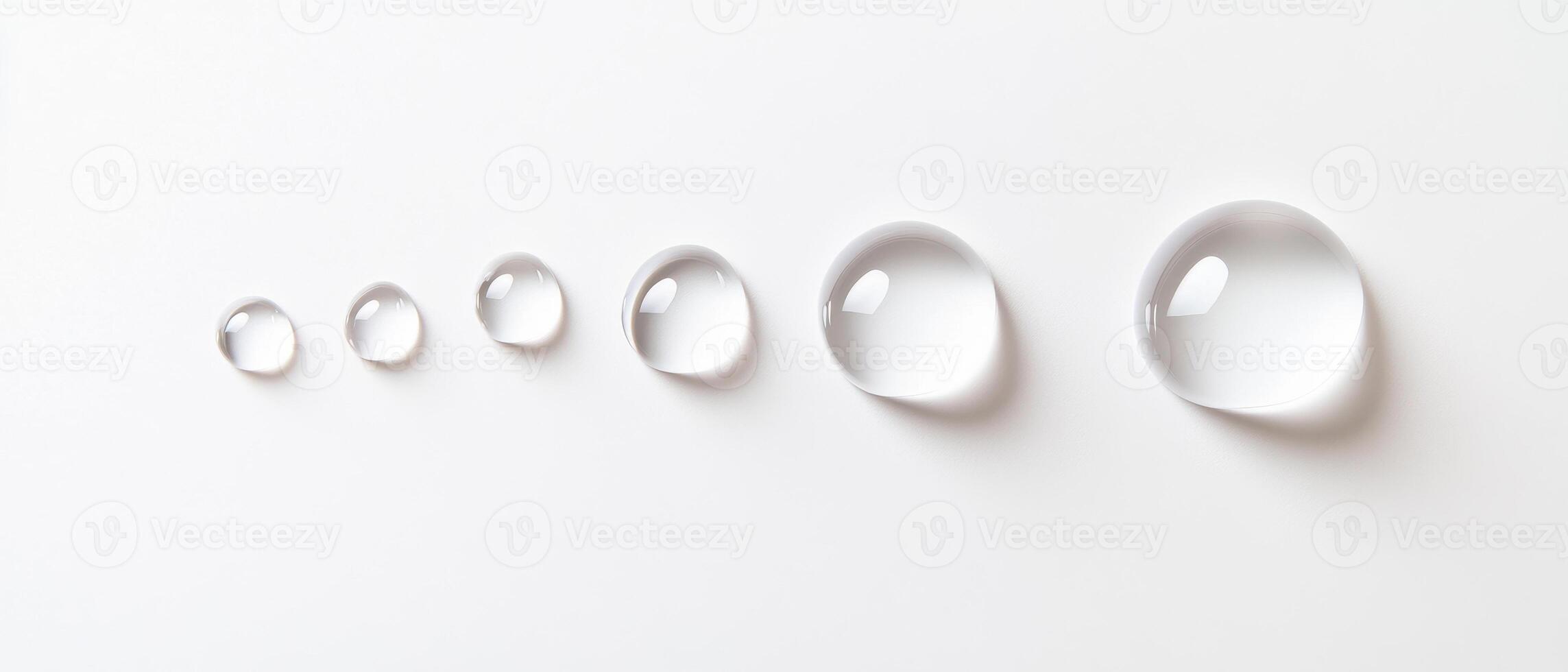 Clear water droplets of varying sizes arranged in line on white background, creating serene and minimalist aesthetic photo