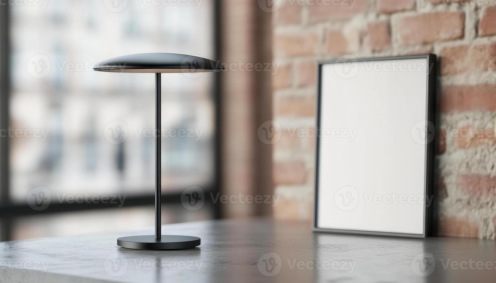 Modern black lamp on concrete table beside blank frame against brick wall, creating stylish and minimalistic interior design photo