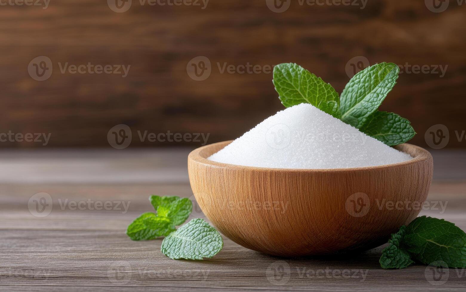 Fresh mint leaves surround bowl of white sugar, creating natural and inviting scene. wooden bowl adds warmth, while mint enhances freshness of composition photo