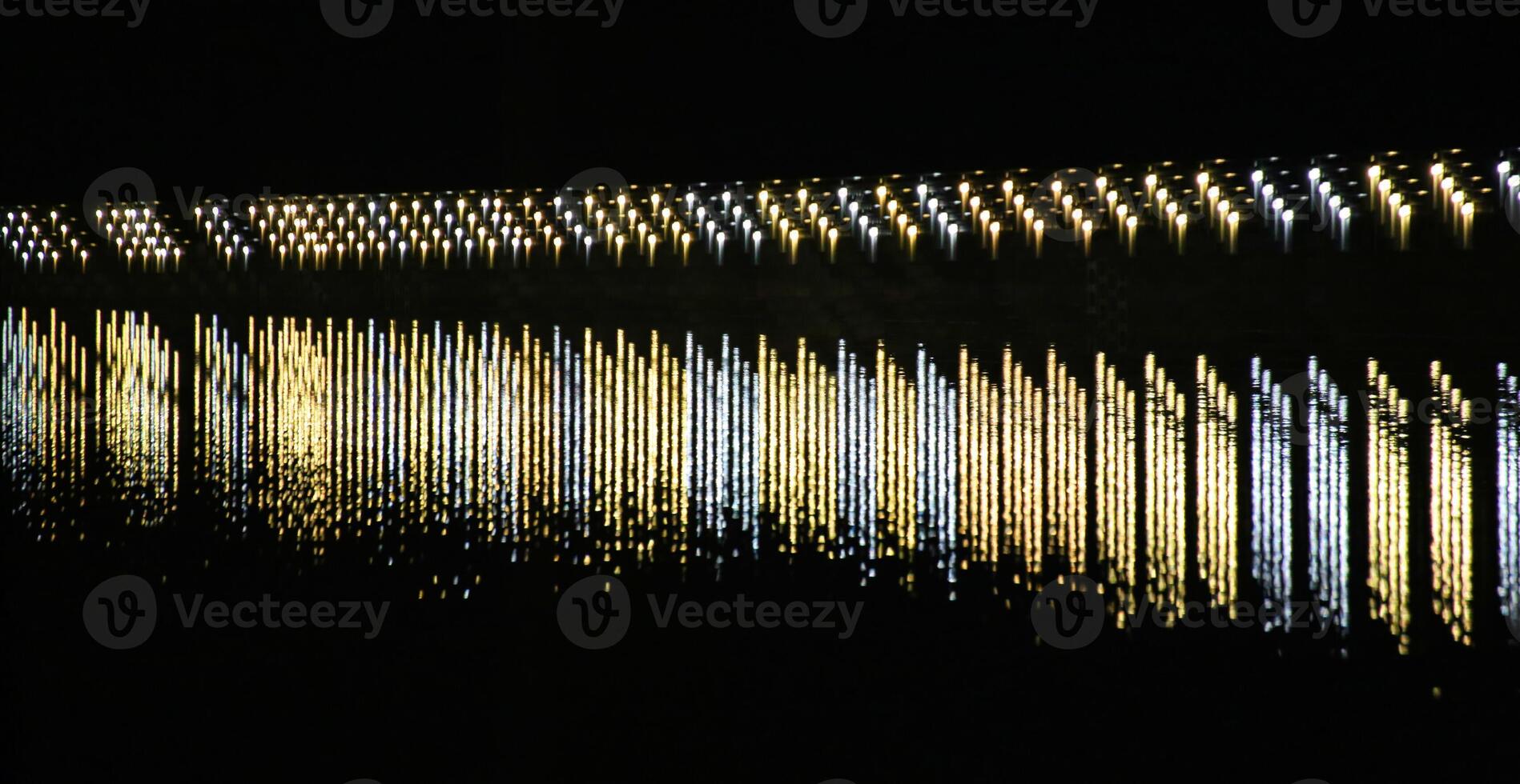 Row of lights reflected on a river. The lights are staggered creating a dense arrangement. photo