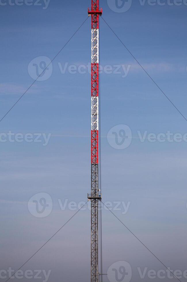 Symmetric view of red and white radio tower. photo