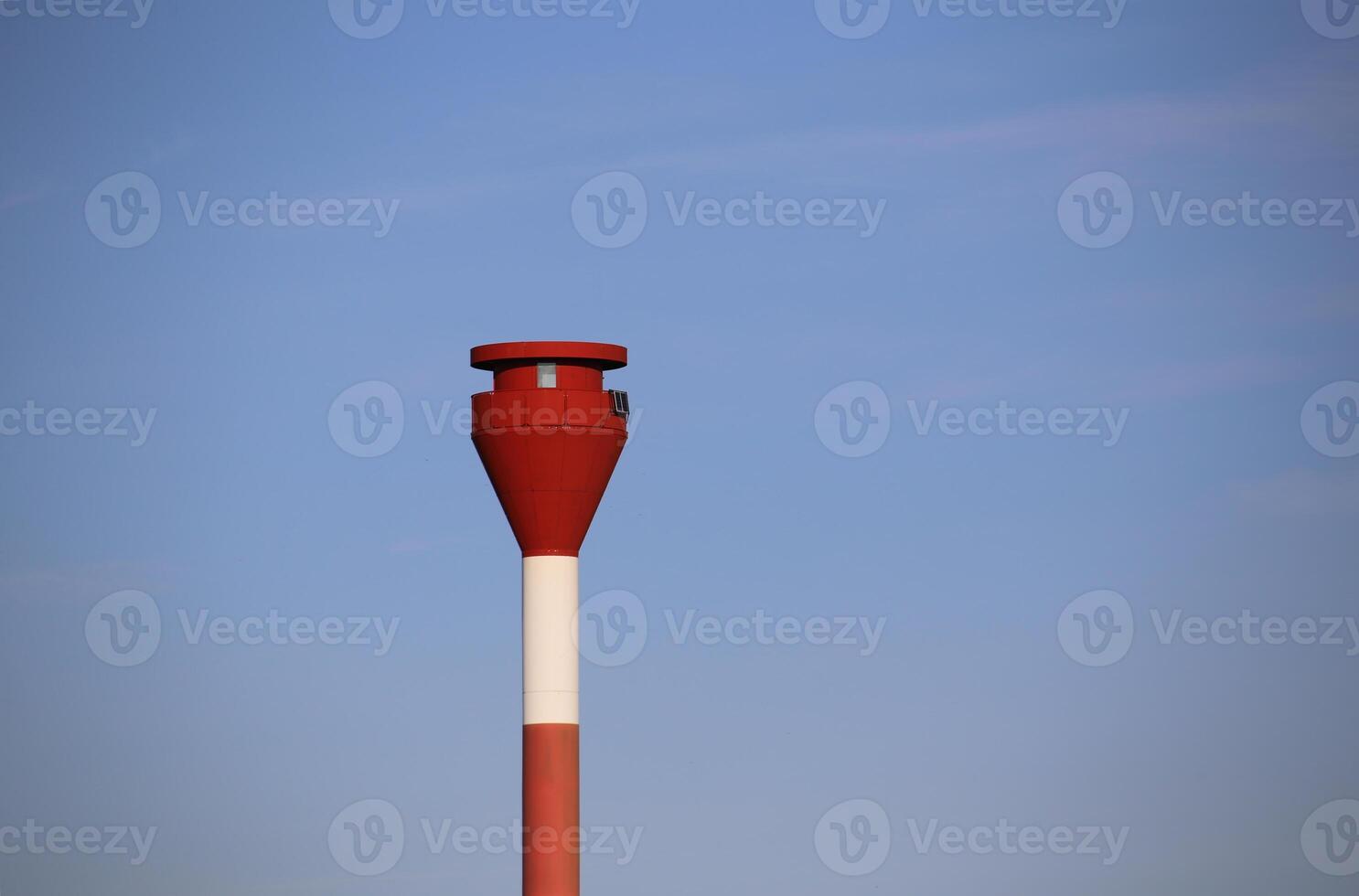 Modern red and white striped lighthouse on blue sky seen from an unusual wide angle directly from below. Rostock, Mecklenburg-Vorpommern, Germany photo