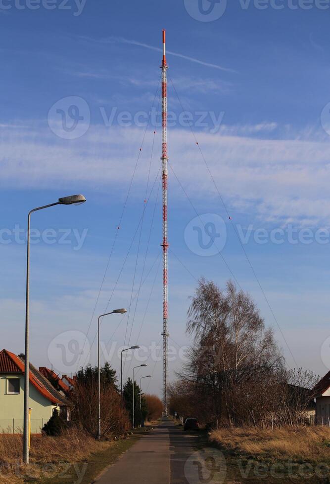 Small street leading to a red and white radio tower photo