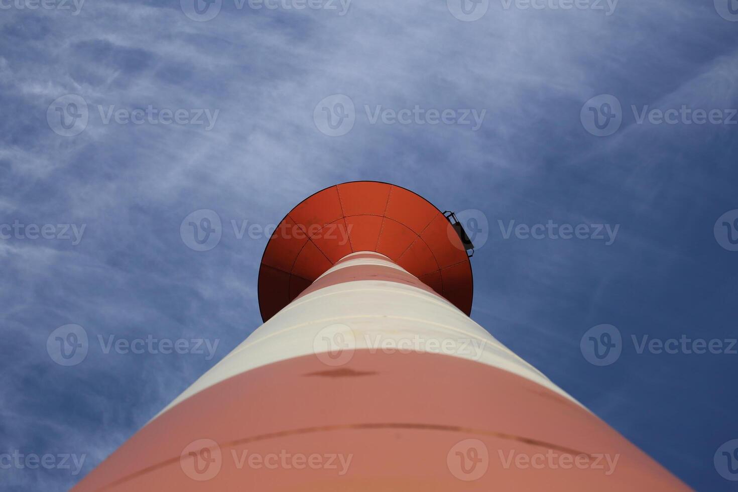 Modern red and white striped lighthouse on blue sky seen from an unusual wide angle directly from below. Rostock, Mecklenburg-Vorpommern, Germany. photo