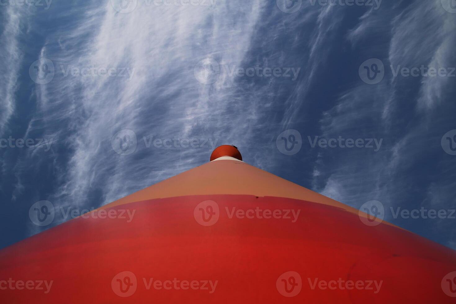Modern red and white striped lighthouse on blue sky seen from an unusual wide angle directly from below Rostock, Mecklenburg-Vorpommern, Germany photo