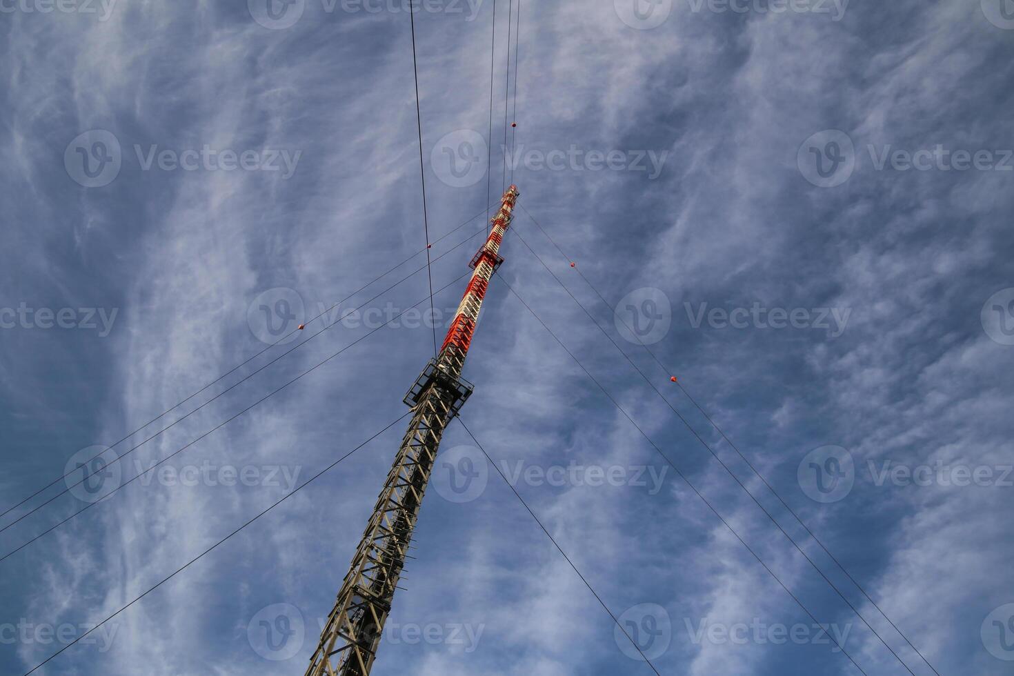 Red and white radio tower in unusual angle photo