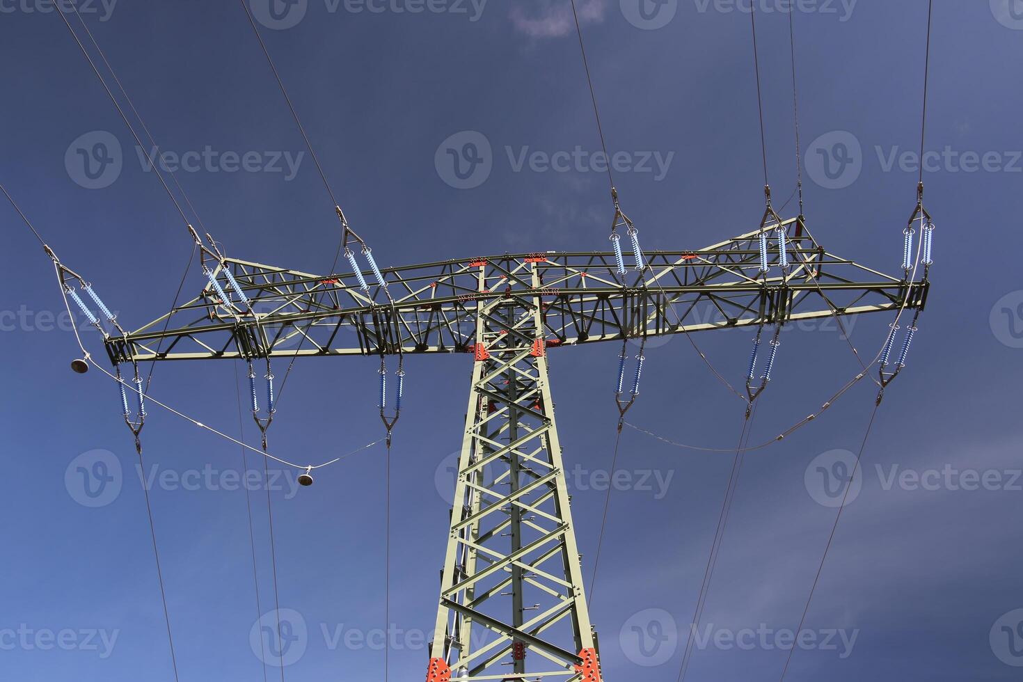 View of a high voltage line pylon and dark blue sky from below. photo