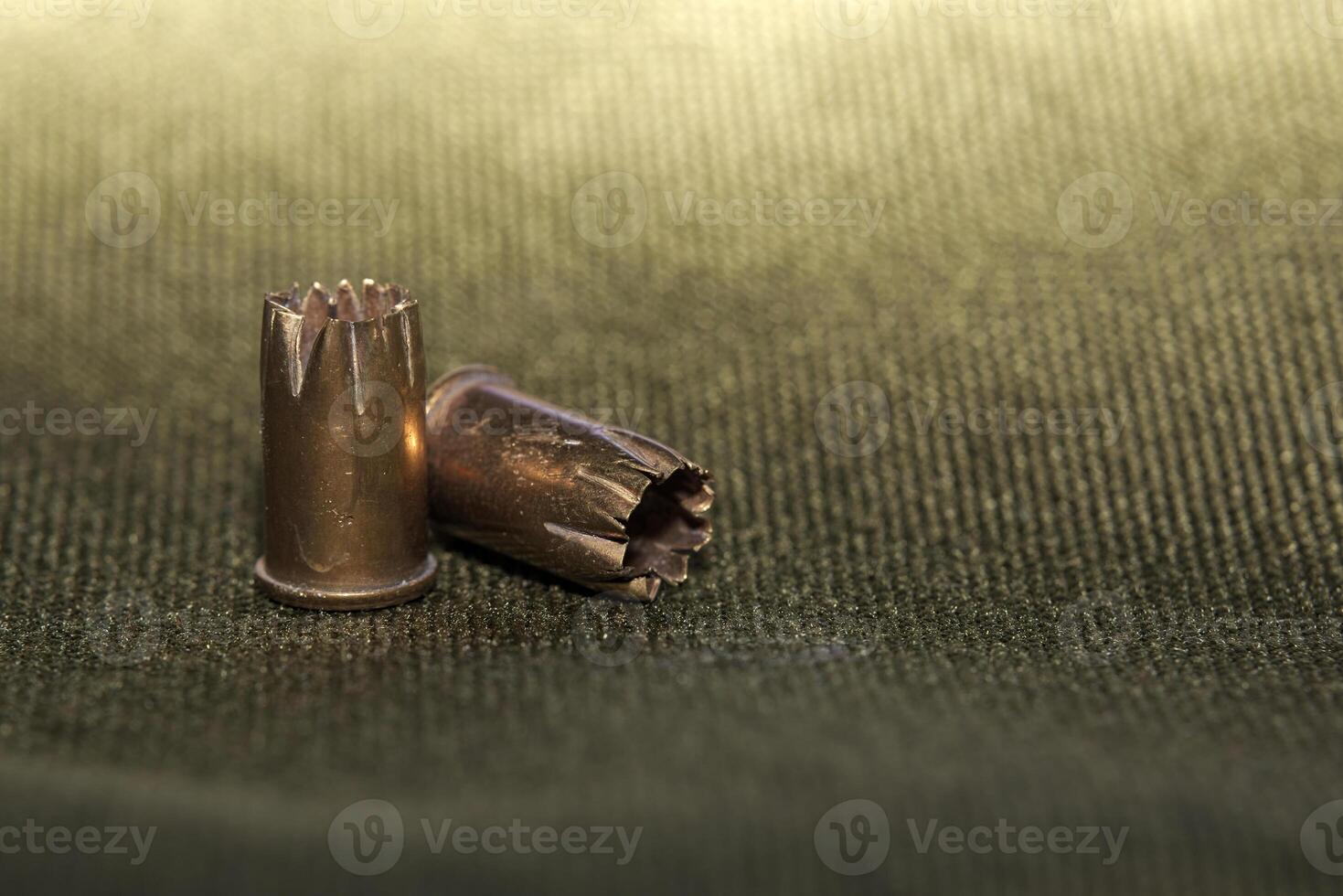 Bullet casings on green textile with selective focus and unusual lighting photo