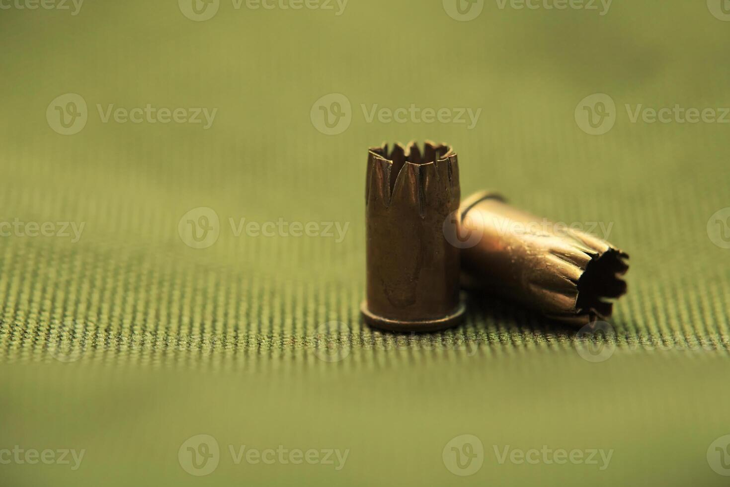 Bullet casings on green textile with selective focus and unusual lighting. photo